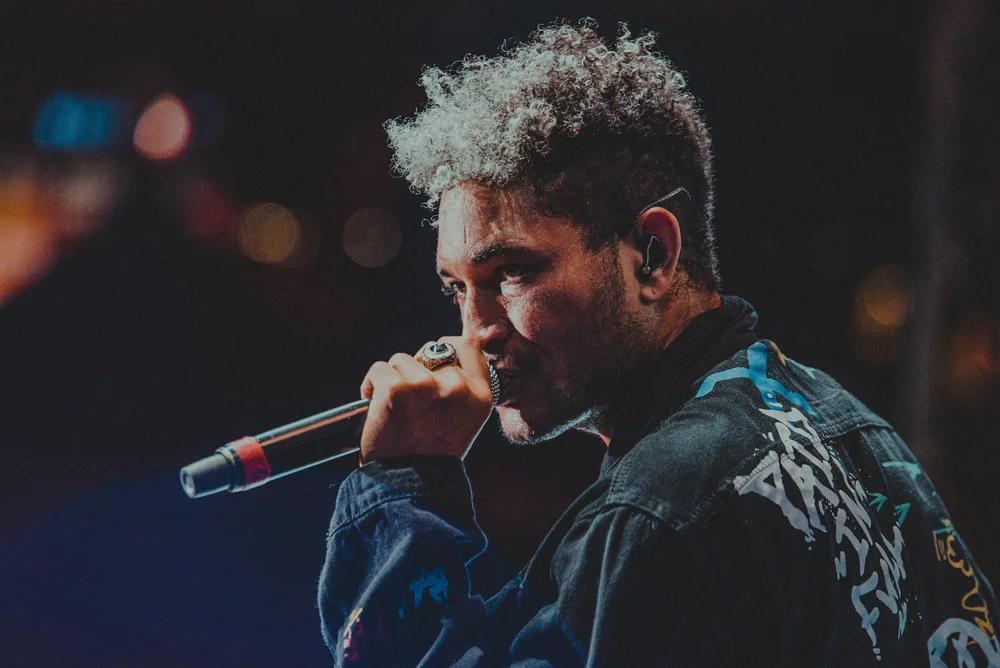 A singer holding a microphone against a dark concert backdrop