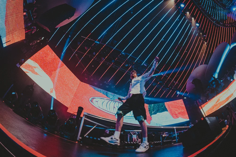 A performer below a sweeping geometric stage display