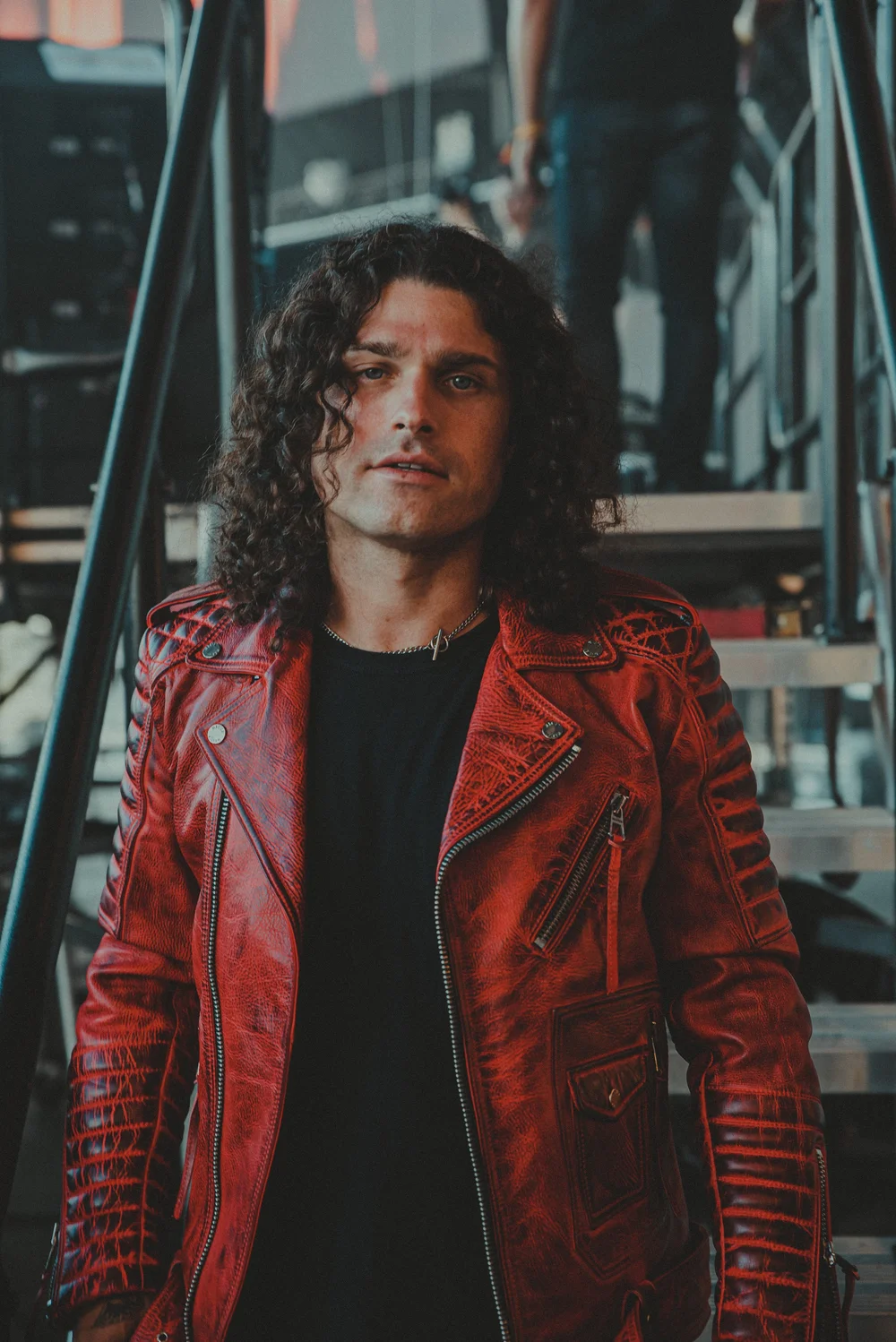 A portrait in a red jacket beside a reflective window